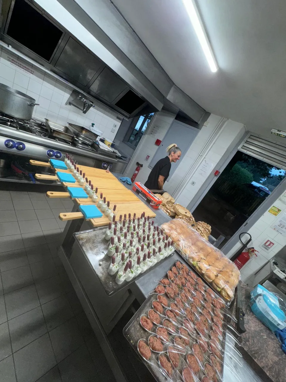 Préparation d’un buffet en cuisine professionnelle : planches en bois, verrines et cuillères de tartare alignées sur le plan de travail
