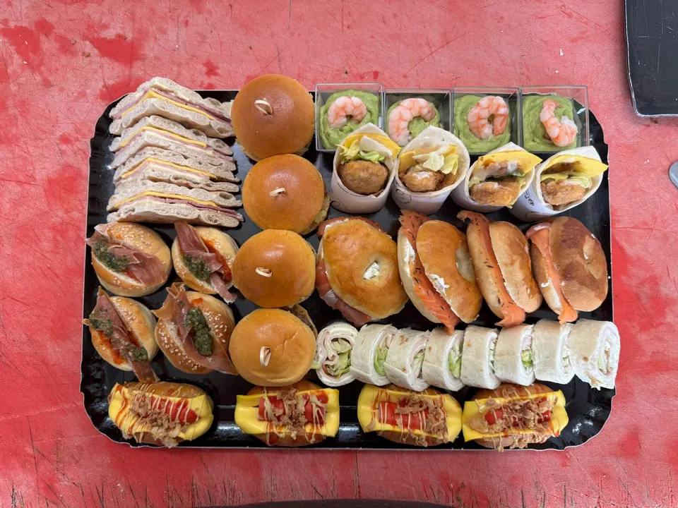 Plateau cocktail vu de dessus : club sandwichs, mini burgers, bagels au saumon, wraps, verrines de crevettes et mini hot-dogs