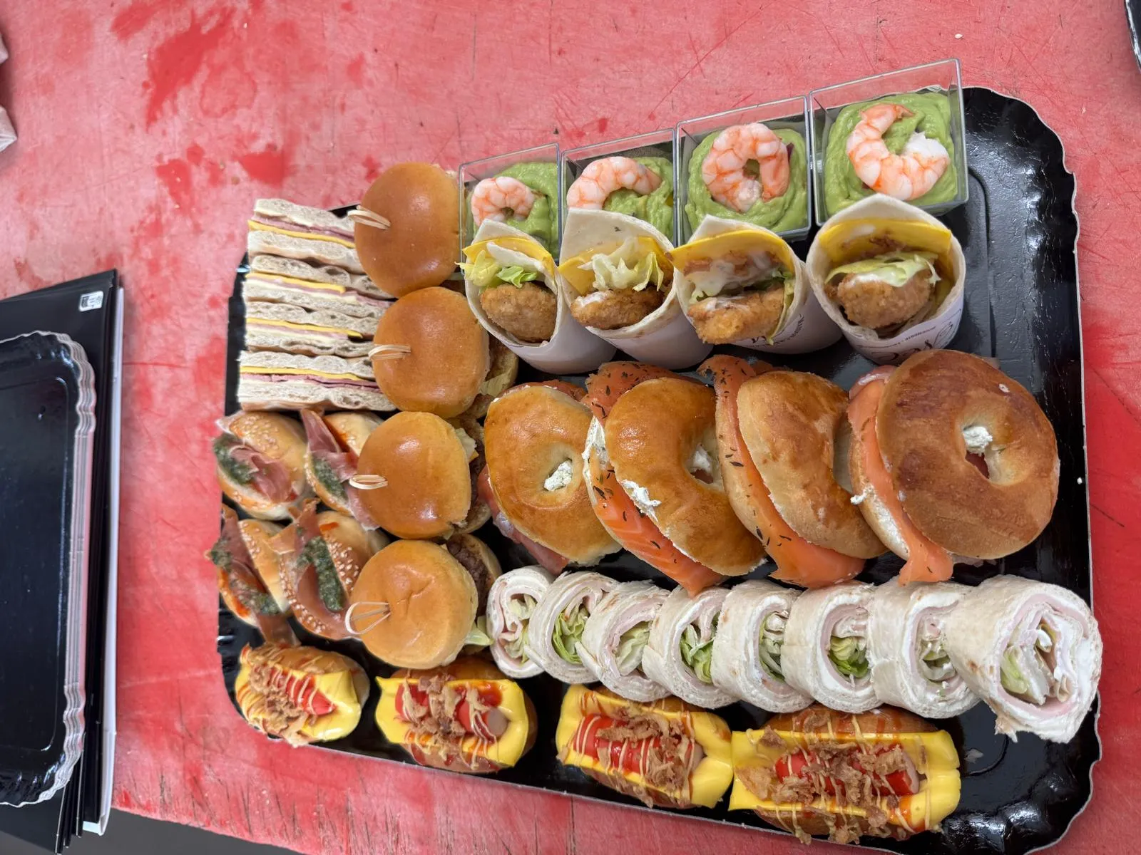 Plateau cocktail garni de bagels au saumon, mini burgers, cornets de wraps, verrines de crevettes et mini hot-dogs